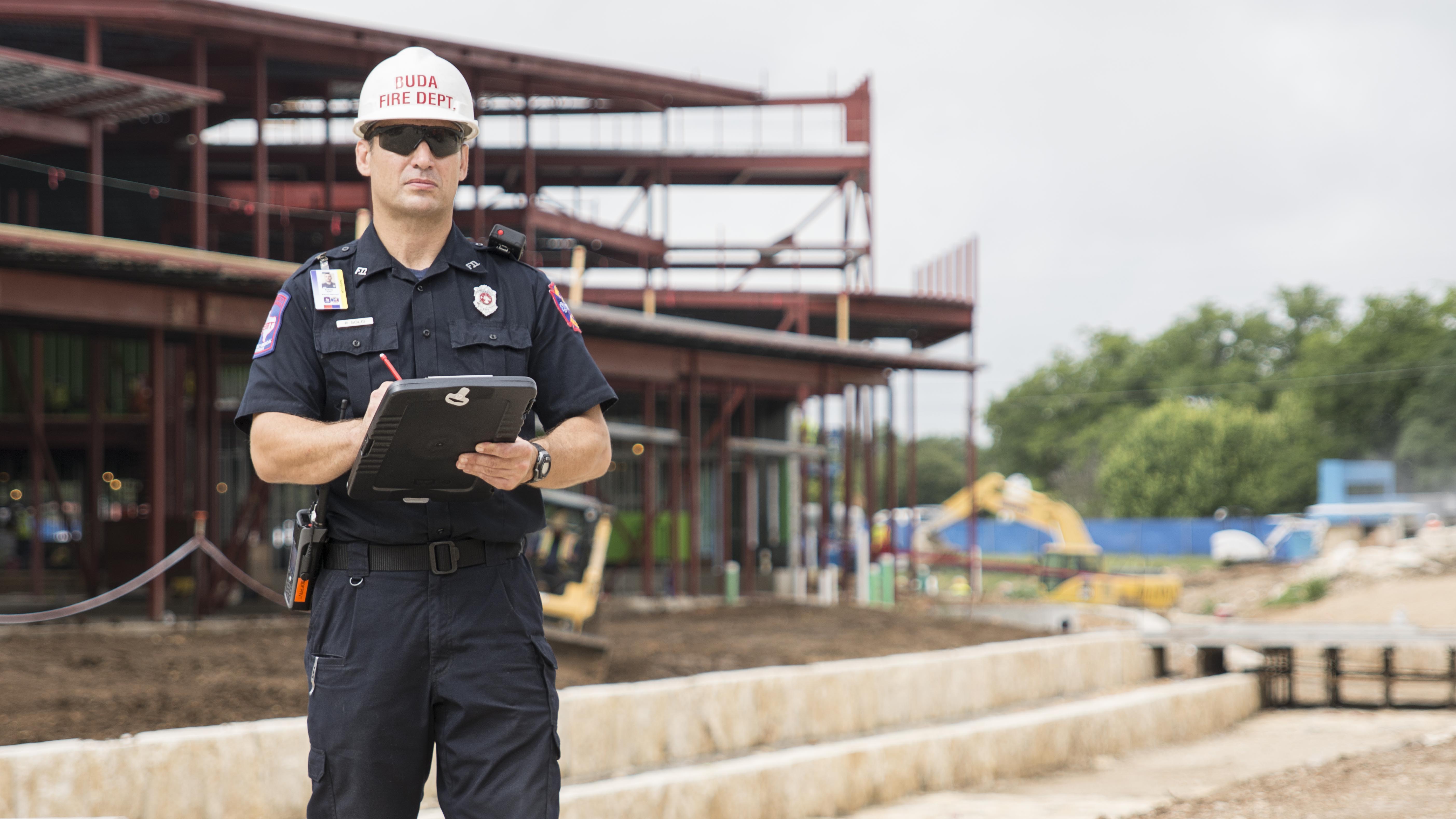 Man standing with clipboard in front of building construction